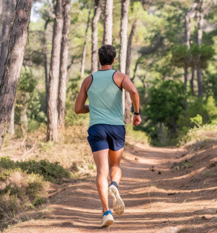 ersona corriendo por un sendero rodeado de naturaleza, símbolo de la vitalidad y bienestar que aporta NUALAT.