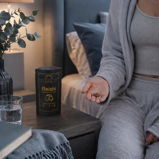 Rutina de Reishi NUALAT con pouch y cápsulas junto a un vaso de agua